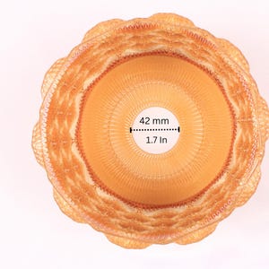 May include: Overhead view of a woven, light brown basket with a scalloped edge. The center opening is 1.7 inches (42 mm) in diameter. The basket has a circular design with concentric rings.