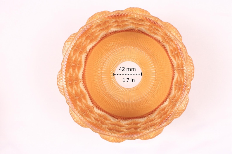 May include: Overhead view of a woven, light brown basket with a scalloped edge. The center opening is 1.7 inches (42 mm) in diameter. The basket has a circular design with concentric rings.