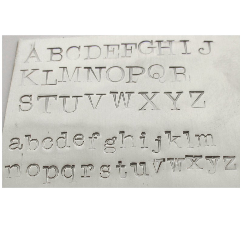 Puede incluir: Primer plano de una placa de metal con el alfabeto en letras may&uacute;sculas y min&uacute;sculas.