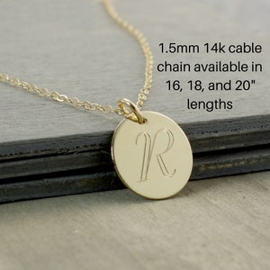 May include: Gold initial necklace with a 1.5mm 14k cable chain. The pendant is a round disc with the letter "R" engraved on it. The chain is available in 16, 18, and 20 inch lengths.