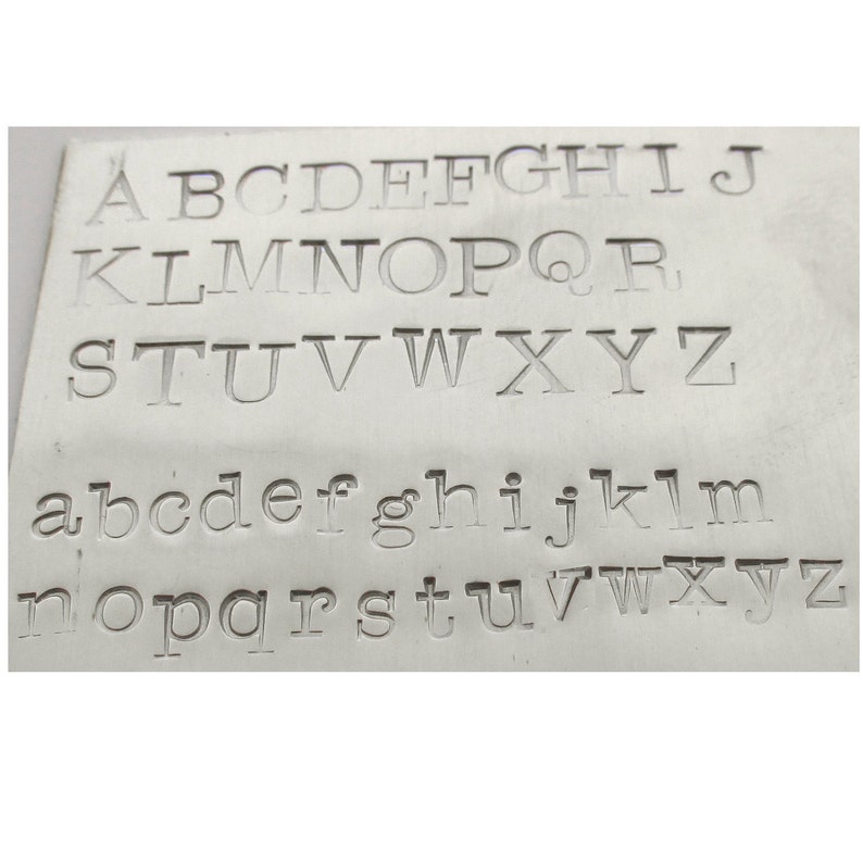 May include: A close-up image of a metal plate with the alphabet printed in uppercase and lowercase letters.
