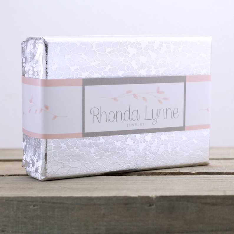May include: A silver gift box with a pink and white label that says "Rhonda Lynne Jewelry".