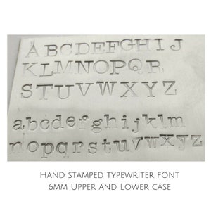 May include: A metal plate with the alphabet in uppercase and lowercase letters, stamped in a typewriter font. The text below reads "HAND STAMPED TYPEWRITER FONT 6MM UPPER AND LOWER CASE".
