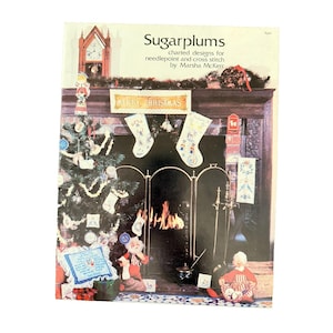 May include: A book cover titled "Sugarplums" featuring charted designs for needlepoint and cross stitch. The image shows a Christmas-themed fireplace scene with a decorated tree, stockings, and a "Merry Christmas" banner.