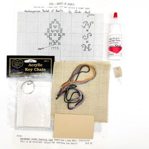 May include: A craft kit for Hardanger embroidery, featuring a chart for a "Basket of Hearts" design. Includes a key chain, fabric, thread, glue, and a teaching tape. The kit is designed for learning the basics of the craft.