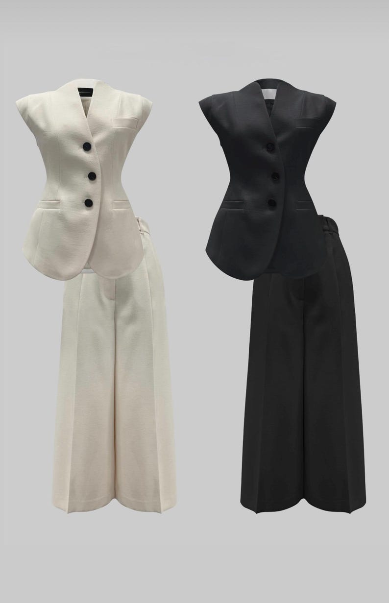 May include: Two matching business suits. One suit is off-white, featuring a vest with three black buttons and wide-leg pants. The other suit is black, with a similar vest and wide-leg pants. Both suits are displayed against a neutral background.