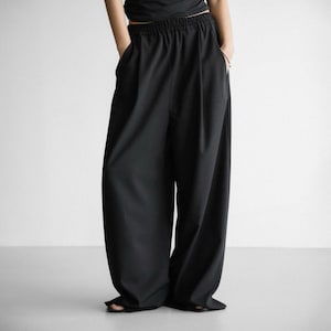 Pu&ograve; includere: Pantaloni neri a gamba larga con vita alta e coulisse. I pantaloni hanno una vestibilit&agrave; rilassata e sono realizzati in un tessuto liscio e leggero.