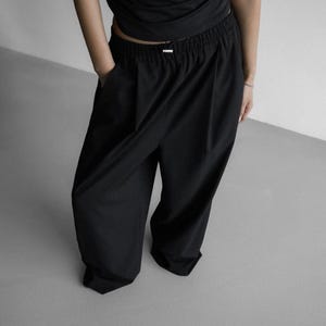 Pu&ograve; includere: Pantaloni neri a gamba larga con vita elastica e vestibilit&agrave; comoda.