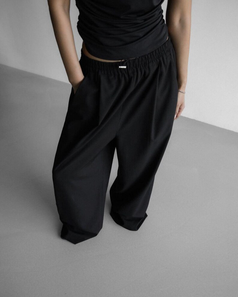 Pu&ograve; includere: Pantaloni neri a gamba larga con vita elastica e vestibilit&agrave; comoda.