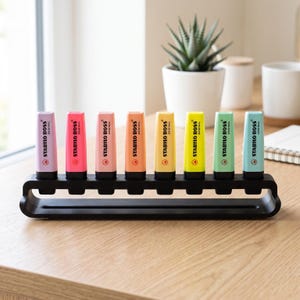 May include: A set of eight Stabilo Boss Original highlighters in various pastel and neon colors, including pink, orange, yellow, green, and blue, arranged in a row within a black, rectangular, open-frame plastic desk organizer stand.