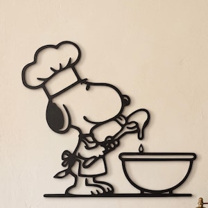 Könnte beinhalten: Ein Wandkunstobjekt aus schwarzem Metall, das die Zeichentrickfigur Snoopy mit Kochmütze und Schürze zeigt, wie sie einen Holzlöffel über eine Rührschüssel hält. Das Design zeichnet sich durch klare, kräftige Linien und eine flache Silhouette aus.