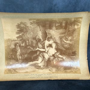 May include: A vintage sepia-toned print of a mythological scene depicting a winged figure with a bow and arrow, embracing a woman. The print is framed in a brown mat and has the text "A. GIRAUDET, Editeur, 15, Passage de Martin, PARIS" at the bottom.