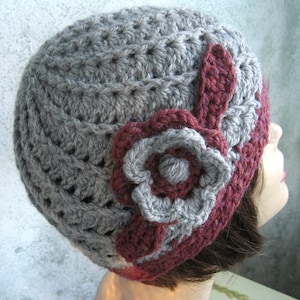 May include: Grey crocheted beanie with a large burgundy flower accent.