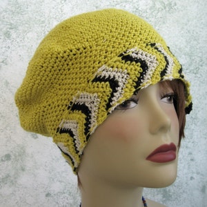 May include: A yellow crocheted beret with a black and white zig-zag pattern around the brim.