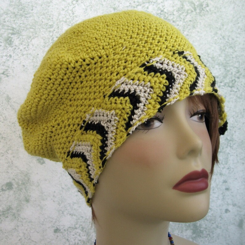 May include: A yellow crocheted beret with a black and white zig-zag pattern around the brim.