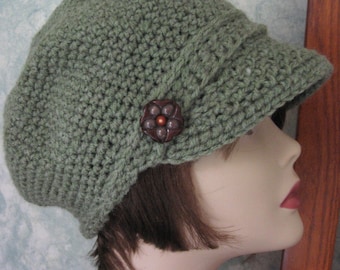 May include: A green crocheted newsboy cap with a brown flower-shaped button.