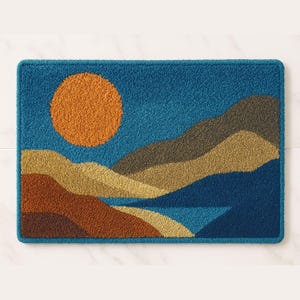 Op de afbeelding: Een rechthoekig tapijt met een landschapsontwerp. Het tapijt heeft een grote oranje zon in een blauwe lucht boven gelaagde bruine, bruine en groene bergen. Het tapijt heeft een donkerblauwe rand en een getextureerd uiterlijk.