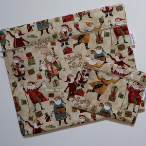 Puede incluir: Dos estuches de tela con cremallera de diferentes tamaños con fondo beige y un patrón repetitivo de figuras de Santa Claus, regalos envueltos y el texto Naughty or Nice? impreso en una fuente cursiva marrón sobre la tela.