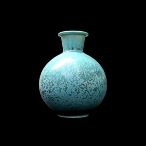 Könnte beinhalten: Eine runde Keramikvase mit engem Hals und ausgestelltem Rand. Die Oberfläche ist mit einer glänzenden türkisfarbenen Glasur überzogen, die ein kristallines Muster aufweist, das von einem helleren Ton oben zu einem tieferen Blaugrün unten verläuft.