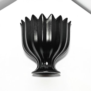 May include: A black ceramic vase with a fluted design and a wide, rounded base.