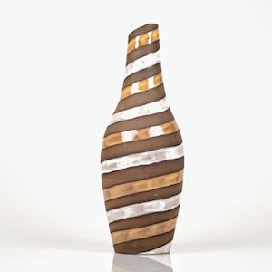 Pode incluir: Um vaso decorativo alto com um pescoço fino e uma base larga. O vaso apresenta um design em espiral de listras horizontais marrons, brancas e douradas alternadas. O vaso é feito de cerâmica ou vidro e está sobre um fundo branco.