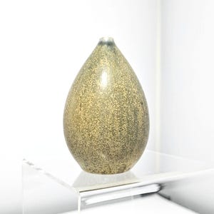 Könnte beinhalten: Eine kleine, tropfenförmige Keramikvase mit einer gesprenkelten, grün-braunen Glasur.