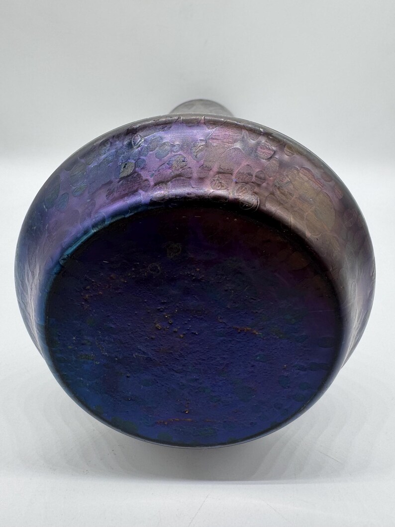 Pu&ograve; includere: Un vaso rotondo e iridescente con una superficie strutturata. Il vaso passa da un viola intenso alla base a una tonalit&agrave; pi&ugrave; chiara e scintillante verso l'alto. Il vaso ha un corpo ampio e arrotondato e un collo stretto.