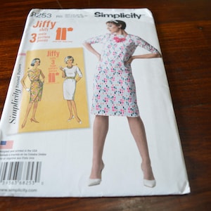 Könnte beinhalten: Ein Simplicity-Schnittmuster für Jiffy-Hemden. Die Musterhülle zeigt eine Frau in einem geblümten Kleid und Illustrationen von Kleiderdesigns. Die Hülle ist weiß mit schwarzem Text und einem Barcode. Die Größe beträgt 28 cm.