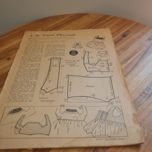 Può includere: Un foglio di cartamodello vintage intitolato 1/2 Yard Playsuit, stampato su carta beige invecchiata con inchiostro nero. Presenta diagrammi tecnici, misure in pollici e istruzioni per la costruzione di un capo d'abbigliamento.