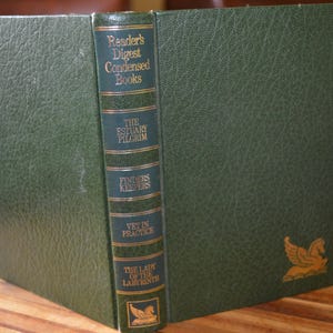 Op de afbeelding: Een groen hardcover boek getiteld "Reader's Digest Condensed Books" met gouden letters. De rug toont titels als "The Estuary Pilgrim" en "Finders Keepers". Een gouden embleem staat op de rechter benedenhoek van de kaft.