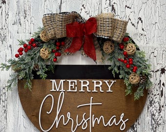 May include: A round wooden door sign with a dark brown finish featuring the white 3D text Merry Christmas. The top is adorned with green pine branches, red berries, small woven rattan spheres, and a large bow made of burlap and black gingham.
