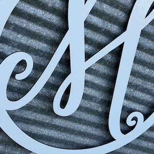 K&ouml;nnte beinhalten: Ein mattwei&szlig;es Wand-Schild aus Metall mit einem gro&szlig;en, kursiven Buchstaben H, der in einem kreisf&ouml;rmigen Rahmen zentriert ist. Das Design ist aus einem einzigen St&uuml;ck Material geschnitten und zeigt glatte, flie&szlig;ende Linien und eine saubere Oberfl&auml;che.