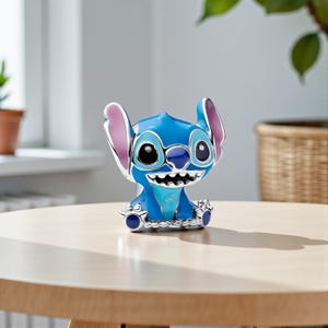 May include: A blue and silver figurine of the character Stitch from the Disney movie Lilo & Stitch. The figurine has large black eyes, a wide grin, and large ears with pink inner ears. It is sitting on a wooden table.