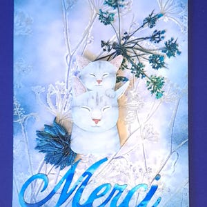 May include: A greeting card with a blue and white design. Two cartoon cats are stacked on top of each other. The word "Merci" is written in blue script at the bottom of the card. The background features floral elements.
