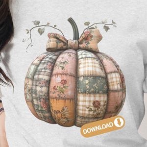 May include: A light gray t-shirt featuring a patchwork pumpkin design. The pumpkin is composed of various fabric patterns, including floral and plaid, in shades of pink, green, and orange. A bow and vines with leaves adorn the top. The word "DOWNLOAD" is printed on the bottom right.