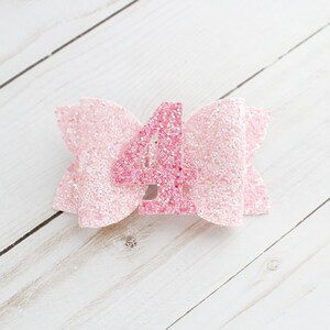May include: Pink glitter bow with a pink glitter number four in the centre.