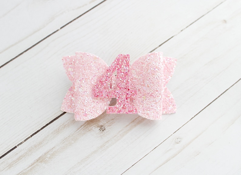 May include: Pink glitter bow with a pink glitter number four in the centre.