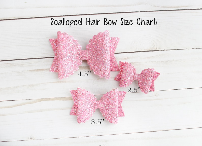 Op de afbeelding: Maattabel voor geschulpte haarstrikken. De tabel toont drie roze glitterstrikken in verschillende maten: 11,4 cm, 8,9 cm en 6,4 cm. De strikken zijn gerangschikt op een wit houten oppervlak.
