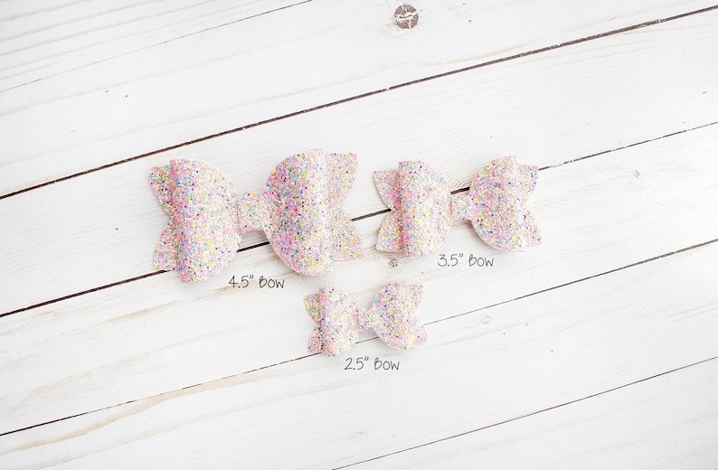 May include: Three pink glitter hair bows of different sizes. The bows measure 4.5 inches, 3.5 inches, and 2.5 inches.