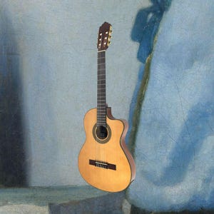 May include: A classical acoustic guitar with a natural wood finish. The guitar has a cutaway design, a dark fretboard, and a rosette around the sound hole. The headstock is a darker wood color. The guitar is set against a blue background.