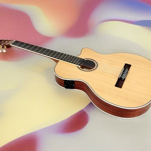 May include: A natural wood acoustic guitar with a cutaway body and a light brown finish. The guitar has a black pickguard and a white binding around the body.