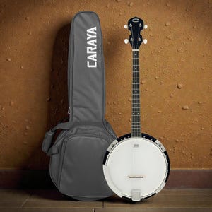 May include: A banjo with a white drumhead and a black neck, next to a gray carrying case with the word "CARAYA" in white. The banjo has a black rim and a silver tailpiece. The background is a brown wall.