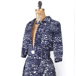 May include: A navy blue and white patterned dress with a V-neckline and short sleeves. The dress has a fitted bodice and a full skirt.