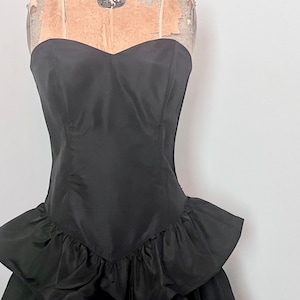 May include: A black strapless dress with a sweetheart neckline and a ruffled skirt.