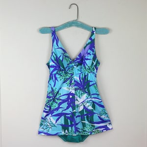 May include: A blue and green swimsuit with a floral print. The swimsuit has a V-neck and a skirt.