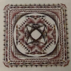 May include: A square piece of fabric with a brown and pink geometric design embroidered on it. The design is made up of lines and circles, and it is surrounded by a border of smaller designs.