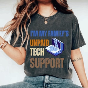 以下が含まれることがあります： 「I'M MY FAMILY'S UNPAID TECH SUPPORT」と青、オレンジ、茶色で書かれた濃い灰色のTシャツ。ラップトップのグラフィックも特徴です。このシャツはカジュアルウェアです。