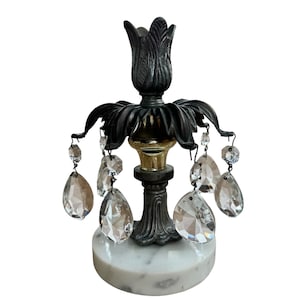 May include: A black metal candlestick with a marble base and crystal drops. The candlestick has a floral design and a gold accent.