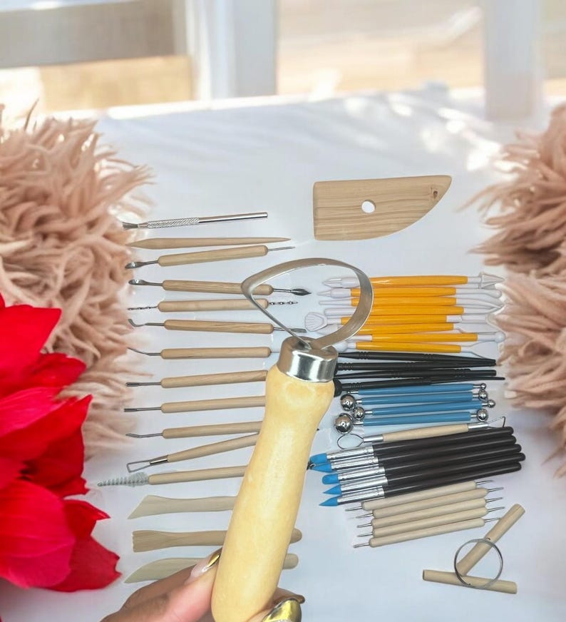 K&ouml;nnte beinhalten: Ein Set an T&ouml;pfereiger&auml;ten zum Modellieren und Formen von Ton. Das Set enth&auml;lt eine Vielzahl von Werkzeugen mit Holzgriffen und Metallspitzen sowie ein Holz-Formwerkzeug.