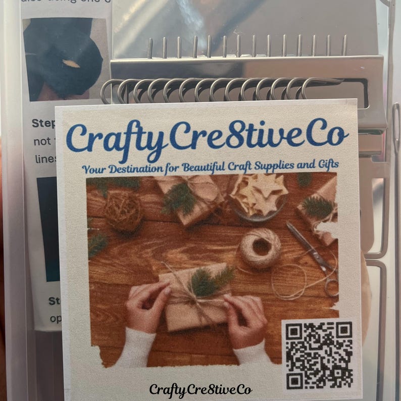 May include: A Crafty Crestive Co. product package with a printed label. The label features the company name in blue script, the tagline "Your Destination for Beautiful Craft Supplies and Gifts", and a photo of wrapped gifts. A QR code is also visible.